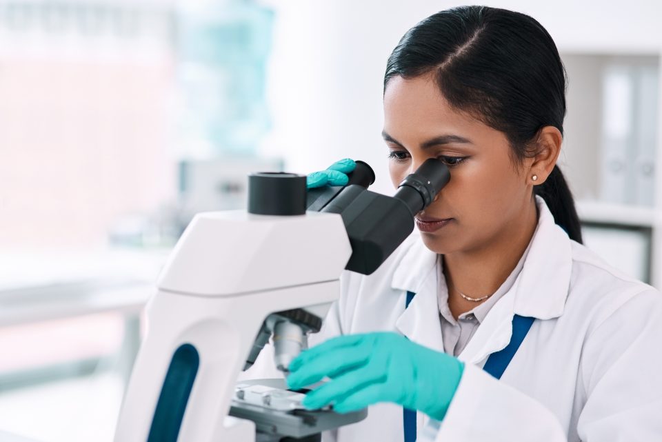 Cropped shot of an attractive young female scientist looking through a microscope while working in a laboratory.